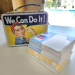 "We Can Do It" Lunchbox with postcards by the pool