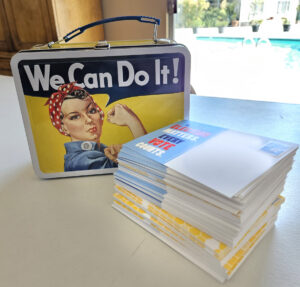 "We Can Do It" Lunchbox with postcards by the pool